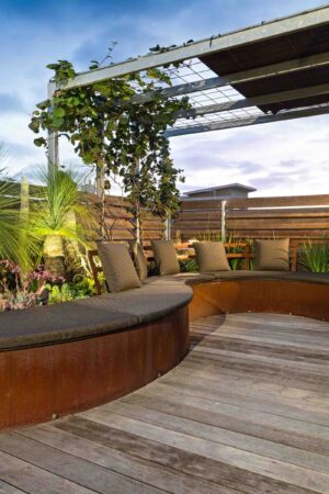 Curved corten steel seating with grey cushions on wooden deck rooftop terrace in Albert Park Melbourne
