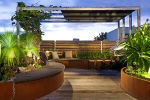 Curved corten steel seating and planters on rooftop terrace with timber decking and tropical plants in Albert Park Melbourne