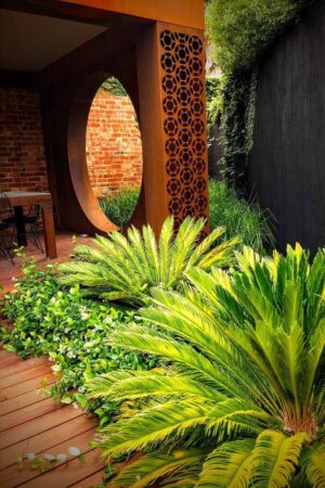 Custom corten steel pergola with circular opening and decorative screen panels in Brighton East courtyard garden