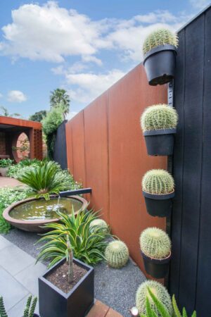 Custom corten steel pergola with barrel cacti planters and circular water feature in Brighton East modern courtyard