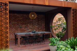 Custom corten steel pergola with geometric screening shelters outdoor dining table in Brighton East modern courtyard