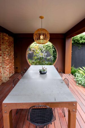 Custom corten steel pergola with integrated concrete fireplace and circular water feature in Brighton East courtyard