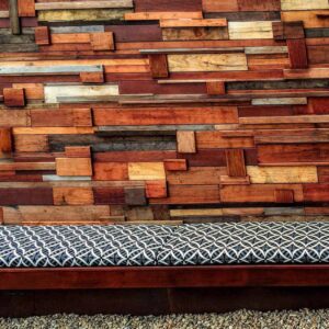 Reclaimed timber feature wall with varied wood tones and geometric patterned outdoor bench seating in Brighton East courtyard