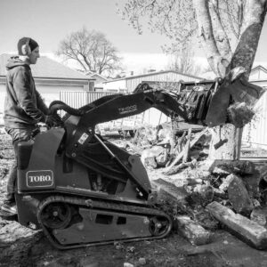 Operator using Toro TX1000 compact track loader for excavation work during Brighton East courtyard construction