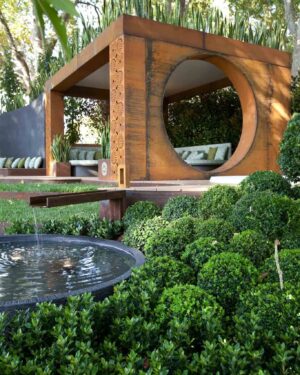Elevated timber pavilion with large circular opening and decorative screen wall beside round water feature in Melbourne