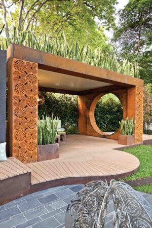 Corten steel pergola with circular opening over timber deck in modern outdoor entertaining space