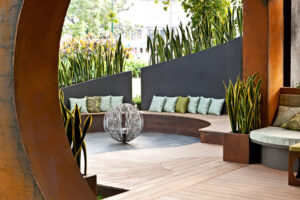 Curved concrete seating with mint cushions arranged around sculptural sphere centerpiece in Melbourne show garden