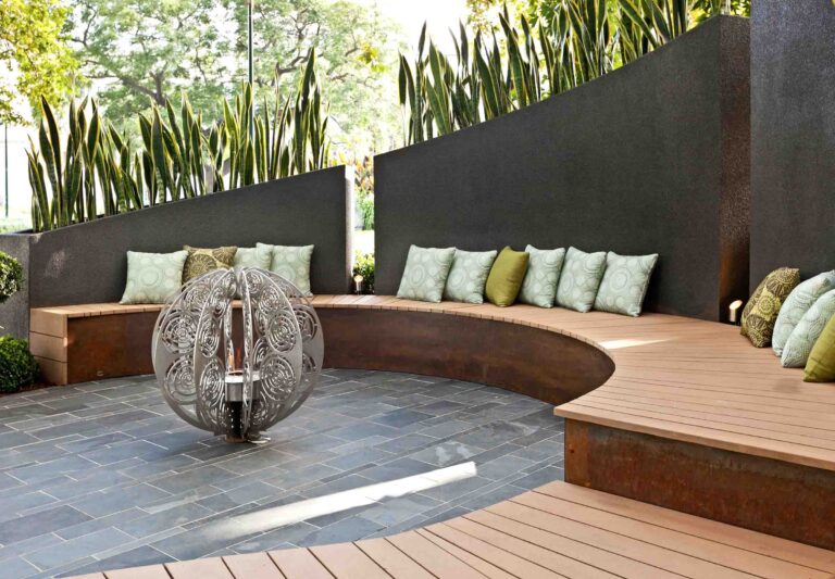 Curved timber bench seating with green cushions around decorative water feature in contemporary Melbourne show garden