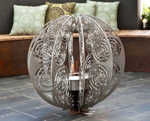 Sculptural steel sphere water feature with intricate cut patterns in contemporary courtyard
