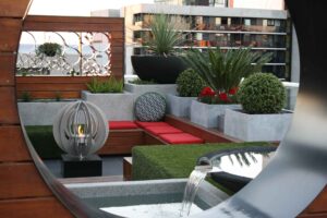 Modern rooftop garden with spherical fire feature, concrete planters, timber seating and water element in Docklands Melbourne