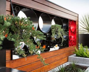 Black and red circular pipe planters with succulents and native plants on timber-framed Docklands rooftop terrace