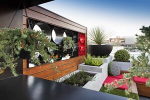 Modern rooftop garden with circular metal screen feature, timber seating and native plantings in Docklands Melbourne