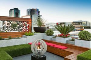 Modern rooftop garden with timber decking, built-in seating, concrete planters and city views in Docklands Melbourne