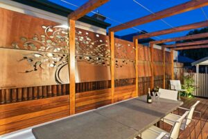 Laser-cut corten steel screens with timber pergola creating private outdoor dining area in Hawthorn East courtyard