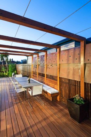 Timber pergola with dining table and laser-cut corten steel privacy screens in Hawthorn East courtyard garden