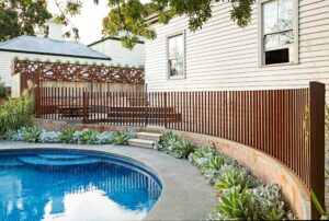 Circular blue pool surrounded by curved corten steel and corten fencing with succulent plantings in Hawthorn residence