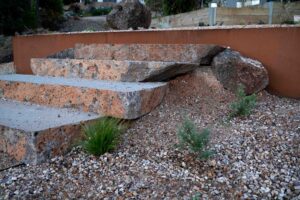 Tiered corten steel retaining walls with native plantings and gravel pathways at Separation Creek coastal property