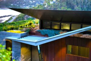 Modern home with flame-zone compliant green roof and tiered corten steel terraces stepping down coastal slope at Separation Creek