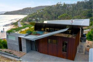 Modern coastal house with native green roof and corten steel terraces overlooking ocean at Separation Creek Victoria