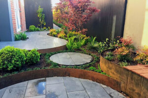 Curved corten steel outdoor room and raised planting beds frame expansive lawn in contemporary Malvern East garden