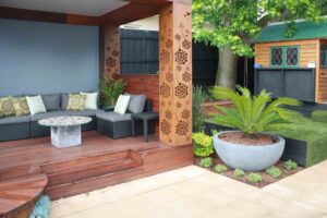 Covered outdoor seating area with decorative corten steel screens and grey cushioned furniture in Malvern East garden