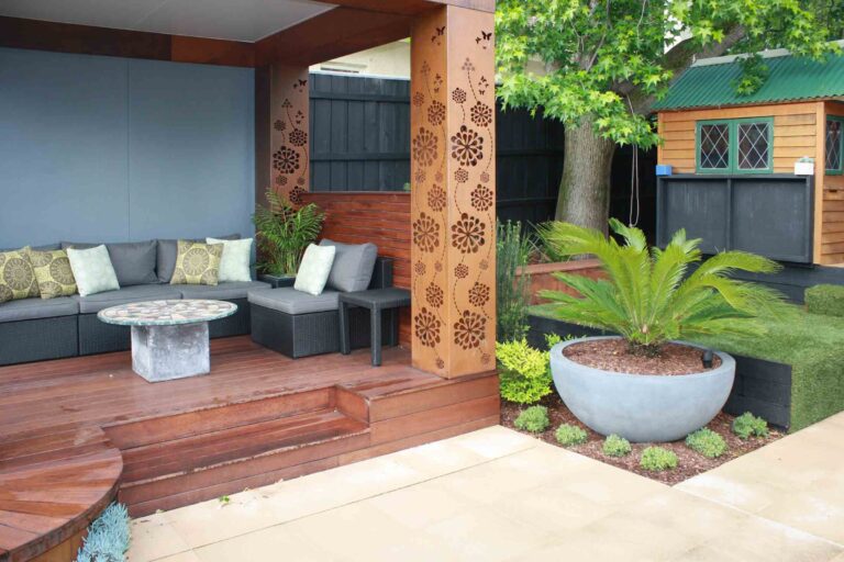 Covered outdoor seating area with decorative corten steel screens and grey cushioned furniture in Malvern East garden