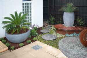 Modern courtyard garden with corten steel planters, palm plants, and stepping stones at Malvern East family home