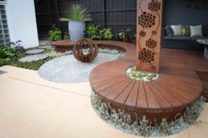 Curved timber decking with corten steel screen and sculptural bottle tree in Malvern East contemporary garden
