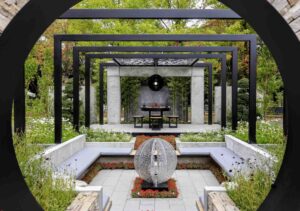 Black circular moon gate frames formal garden with central fire sculpture and symmetrical water features in Nagasaki Japan