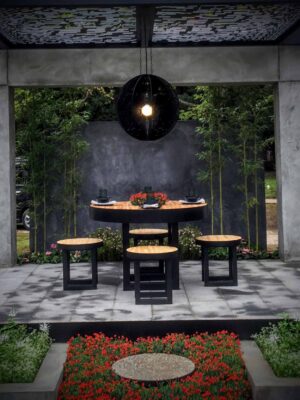 Modern concrete pavilion with round timber dining table and black pendant light, Mandala Moon Gate Garden Nagasaki