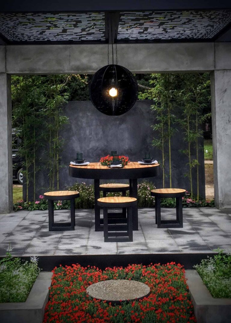 Modern concrete pavilion with round timber dining table and black pendant light, Mandala Moon Gate Garden Nagasaki