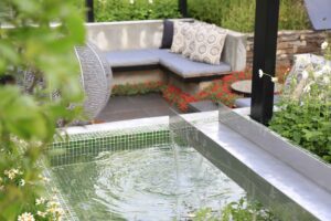 Rectangular water feature with fountain jets and safety mesh, framed by circular moon gate in award-winning Nagasaki garden