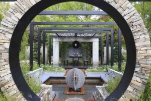 Circular stone moon gate frames modern garden pavilion with water feature and sculptural sphere at Nagasaki Japan