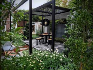 Black steel moon gate framing outdoor dining area with pendant light and lush garden plantings in Nagasaki Japan