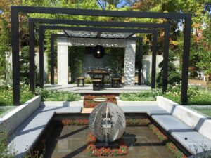 Black steel moon gate pergola frames white dining pavilion with sculptural water feature in award-winning Nagasaki garden