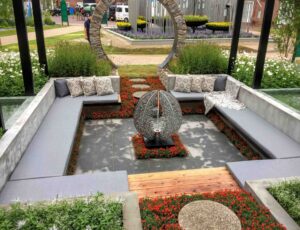 Sunken concrete seating area with central fire sculpture and stone moon gate arch at award-winning Nagasaki garden