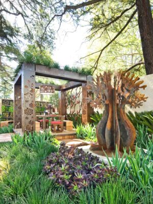 Prefabricated outdoor pavilion with decorative corten steel panels and sculptural tree artwork at Melbourne show garden