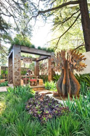 Prefabricated outdoor pavilion with decorative corten steel panels and sculptural tree artwork at Melbourne show garden