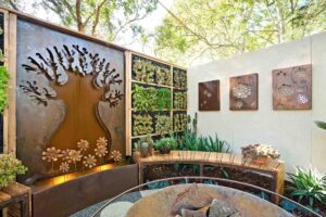 Corten steel tree sculpture wall with integrated fire bowl and curved timber seating at Melbourne International Flower & Garden Show