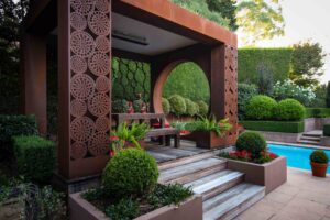 Modern corten steel pavilion with decorative screening beside swimming pool in Mt Eliza formal garden design