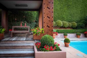Corten steel pavilion with circular perforated screens beside swimming pool in Mt Eliza formal garden design