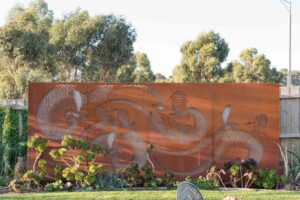 Laser-cut corten steel wattle birds panels against native garden plantings in Buninyong residential landscape design