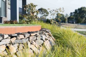 Dry stone retaining wall with native grasses in modern landscape design, Buninyong residential garden project