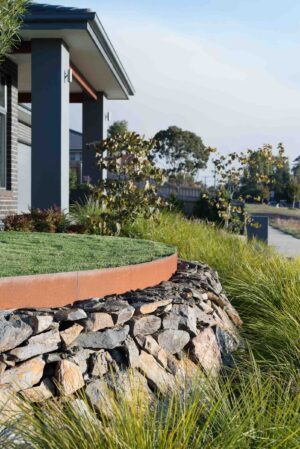 Dry stone retaining wall with corten steel edging and native grasses at corner block residence in Buninyong Victoria