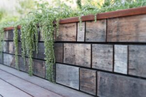 Recycled timber retaining wall with trailing native plants cascading over horizontal timber blocks in Buninyong garden