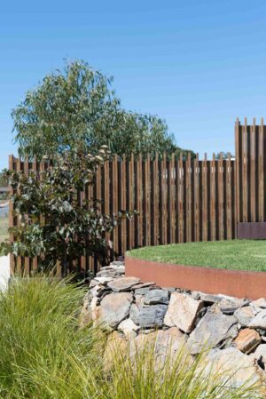 Modern timber screening fence with stone retaining wall and native plantings in Buninyong corner block garden design