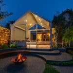 Evening view of Armstrong Street Ballarat garden with curved corten steel bench and central fire pit connecting lawn to covered outdoor living area.