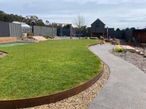 Expansive green lawn bordered by corten edging and gravel path at Gisborne property.