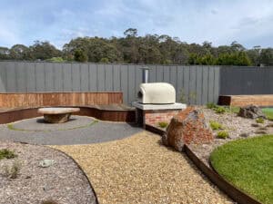 Outdoor lounge seating beside pool with gravel ground plane and feature boulders in Gisborne landscape.