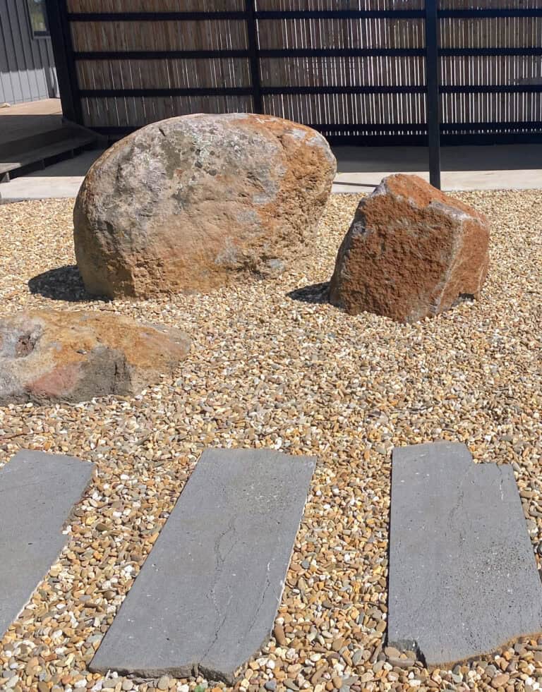 Bluestone stepping stones set in gravel with large natural boulders in Gisborne garden.